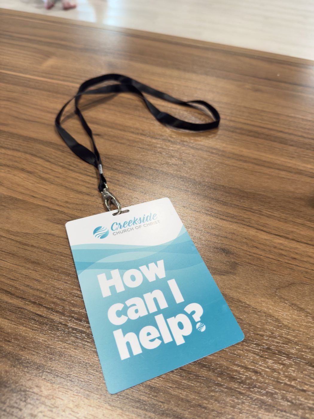Second lanyard card reading How can I help, with the Creekside logo above layered blue waves.